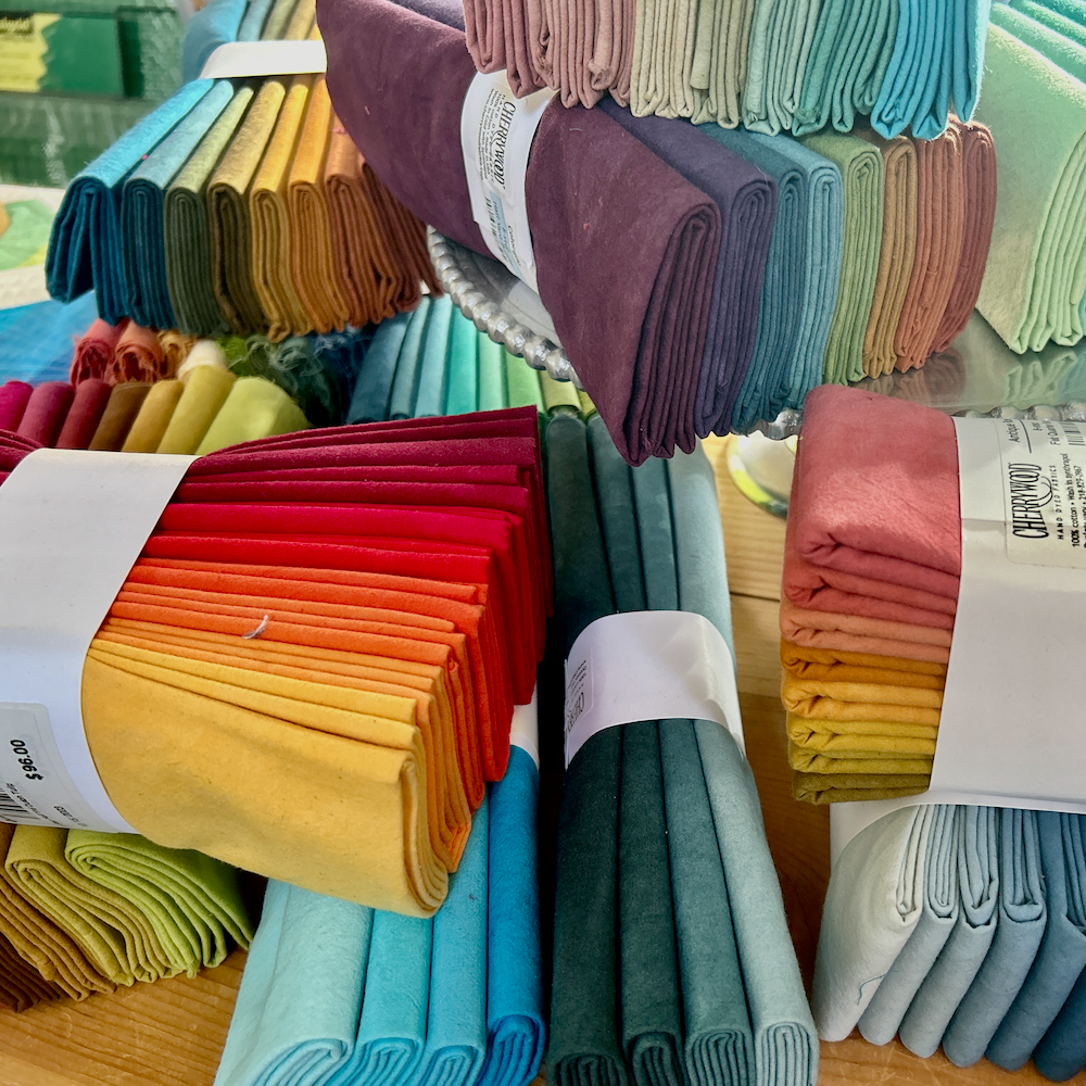 Hand-dyed Cherrywood Half Yard and Fat Quarter Bundles on a table.